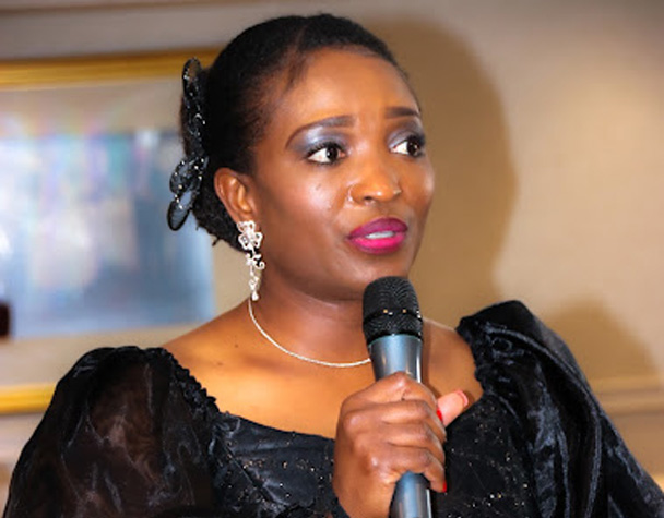 Bukola Jolugbo speaking with a microphone at an event